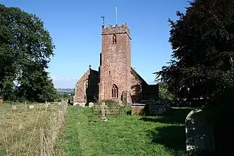 Reddish stone building with square tower.