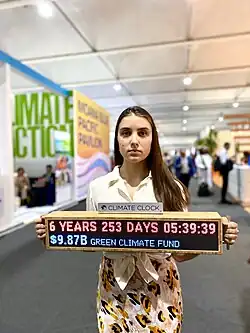 This person holding a sign labeled "Climate Clock."