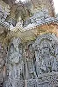 Relief of Hindu deities below lower eve and miniature decorative towers above it (below upper eve) in the Kedareshwara temple at Halebidu