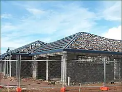 A hip roof construction in Northern Australia showing multinail truss construction. The blue pieces are roll formed metal roof battens or purlins. This roof is built with purpose-made steel hook bracket which is bolted to the truss with M16 bolt. The bracket is bolted to an M16 bolt cast in situ, embedded 300&nbsp;mm (12&nbsp;in) into the reinforced concrete block wall. This system is typically in place every 900&nbsp;mm (35&nbsp;in) around perimeter