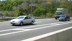 A view from the center of a freeway, looking across to homes on a wooded hill