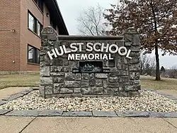 A stone memorial that reads "Hulst School Memorial 1899 1949"​​‌