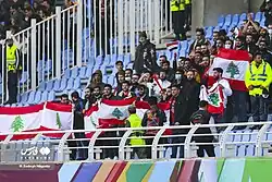 Football supporters holding flags of Lebanon during the 2022 FIFA World Cup qualifiers in Iran