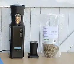 Kaffelogic Nano 7 coffee roaster, pictured next to a bag of green beans and scales.