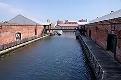 Two joined red gabled brick houses with black roofs and entrances on the gable ends.