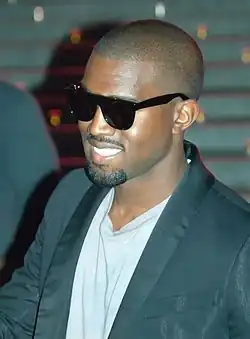 A man wearing a blue T-shirt, a black jacket and sunglasses