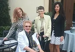 four women in picture, three standing, one sitting in front