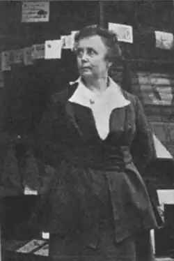 B&W photo of a middle-aged woman wearing a black outfit with white blouse