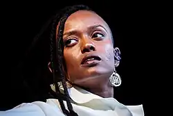 In the stage lighting, framed against darkness, Kelela turns her head and looks to the side