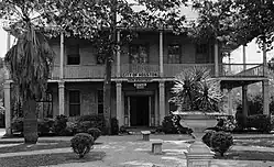 Brick two-storey gambral-roofed house with gracious wrap-around porch and second story balcony with columns. Square columns on first floor porch are of brick.