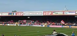 One of the stands of the Bootham Crescent association football ground, with supporters waving flags and a grass field below