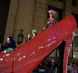 parade float shaped like a shoe, woman with long red hair riding