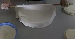 Petë placed atop an oiled tepsi (pan) using rolling pin