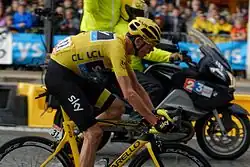 A man wearing a yellow jersey riding a bicycle.