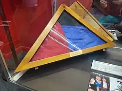 red, blue, and black flag folded within a triangular storage case.