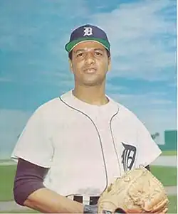 A man in a white baseball jersey and navy blue cap