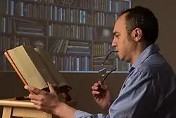 A man reads a book on a lectern.