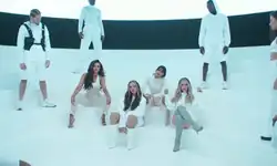 Little Mix on a stage in matching white outfits accompanied by dancers.