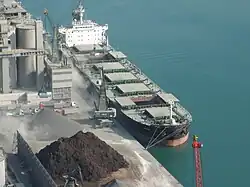A relatively large bulk carrier loading a grey aggregate