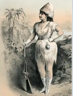 moderately buxom white woman standing, holding a rifle and wearing a costume intended to suggest a castaway