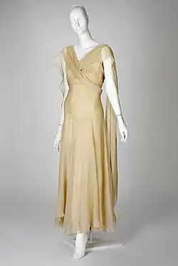 Beige ankle-length sleeveless dress with pieces draped over the shoulder