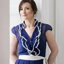 A photograph of Irish singer Margaret Healy wearing a blue dress and white belt. It is set against a white background.
