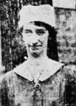 A white woman wearing a cloth cap and dark dress