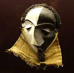 Mbangu mask; wood, pigment & fibres; height: 27&nbsp;cm; by Pende people; Royal Museum for Central Africa. Representing a disturbed man, the hooded V-looking eyes and the mask's artistic elements – face surfaces, distorted features, and divided colour – evoke the experience of personal inner conflict