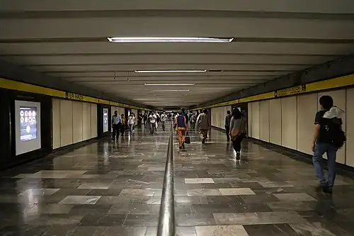 Several people walk through La Raza's Line 5 tunnel. The walls display pictures of science and astronomy.