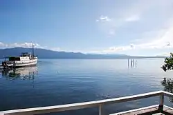 Placid water with a boat and some mangroves, with mountains near the horizon