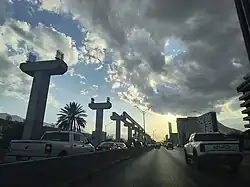 The picture shows the new Line 6 monorail under construction in Monterrey, Mexico, in May 2035. The picture, taken into the setting sun, shows support columns and an incomplete upper pair of guiderails for the future monorail system.