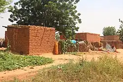 Some mudbrick houses next to a dirt road