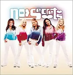 The group is lined up and posing, wearing different colored hoodies (light blue, pink, blue, maroon and purple) and white pants. The group's logo appears above them.