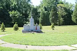 A granite monument with flags and flowes that is inscribed with names