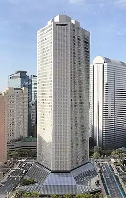 Ground-level view of a gray, window-dotted high-rise