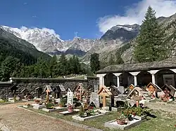 Old Church cemetery graves surrounded by the east wall of Monte Rosa, Macugnaga, Italy