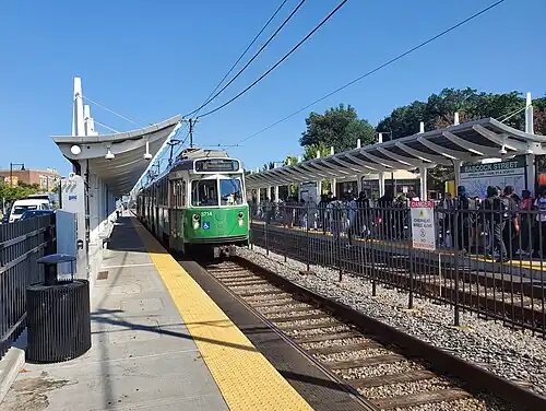 A light rail train at a surface station in the median of an urban street