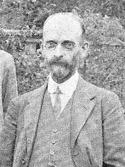 Black-and-white photographic portrait of a bearded gentleman in a suit