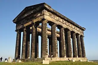 A monument in the style of a Greek temple, made of blackened stone