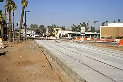 A section of median light rail tracks is installed. However, the roadway on both sides is dirt and not at level