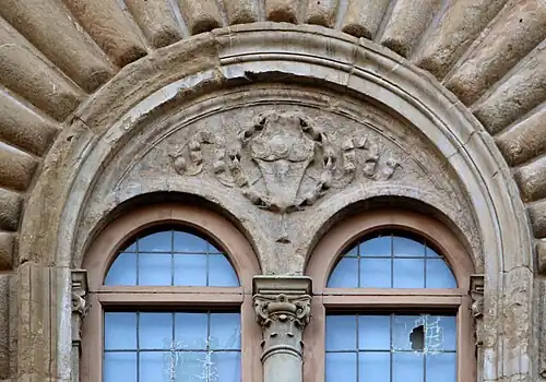 Renaissance cartouche in a laurel crown with ribbons, above a bifora of the Palazzo Strozzi, Florence, Italy, by Benedetto da Maiano, 1489-1538