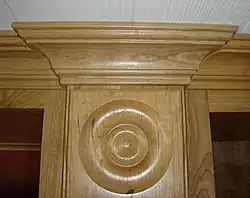 Decorative pilaster of natural cherry hardwood topped with crown molding