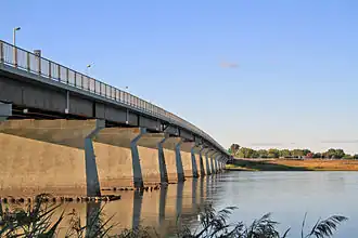A box girder bridge, with a steel truss railway bridge in the background.