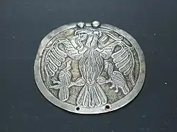 A plaque depicting a bird of prey holding birds in its claws