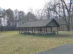 A large open wooden structure in a field