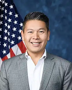 Official House portrait of Tran smiling in front of the U.S. flag, wearing a grey suit and light blue shirt.