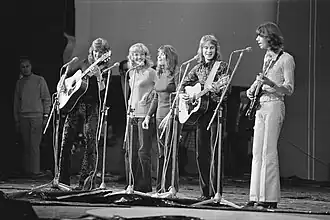 A black-and-white photograph of the 1972 line-up of the New Seekers performing on a television studio set