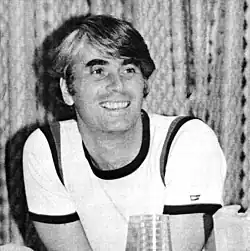Black-and-white photo of smiling man wearing a white T-shirt