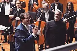 Rodrigo Ruiz acknowledges applause at the premiere of Varuna, R. 12 No. 2, with conductor José Miguel Rodilla and the Orquesta Sinfónica del Estado de México at the Felipe Villanueva Hall in Toluca, Mexico, on 10 March 2023.