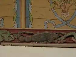 Photograph of a carved and painted beam depicting a scorpion